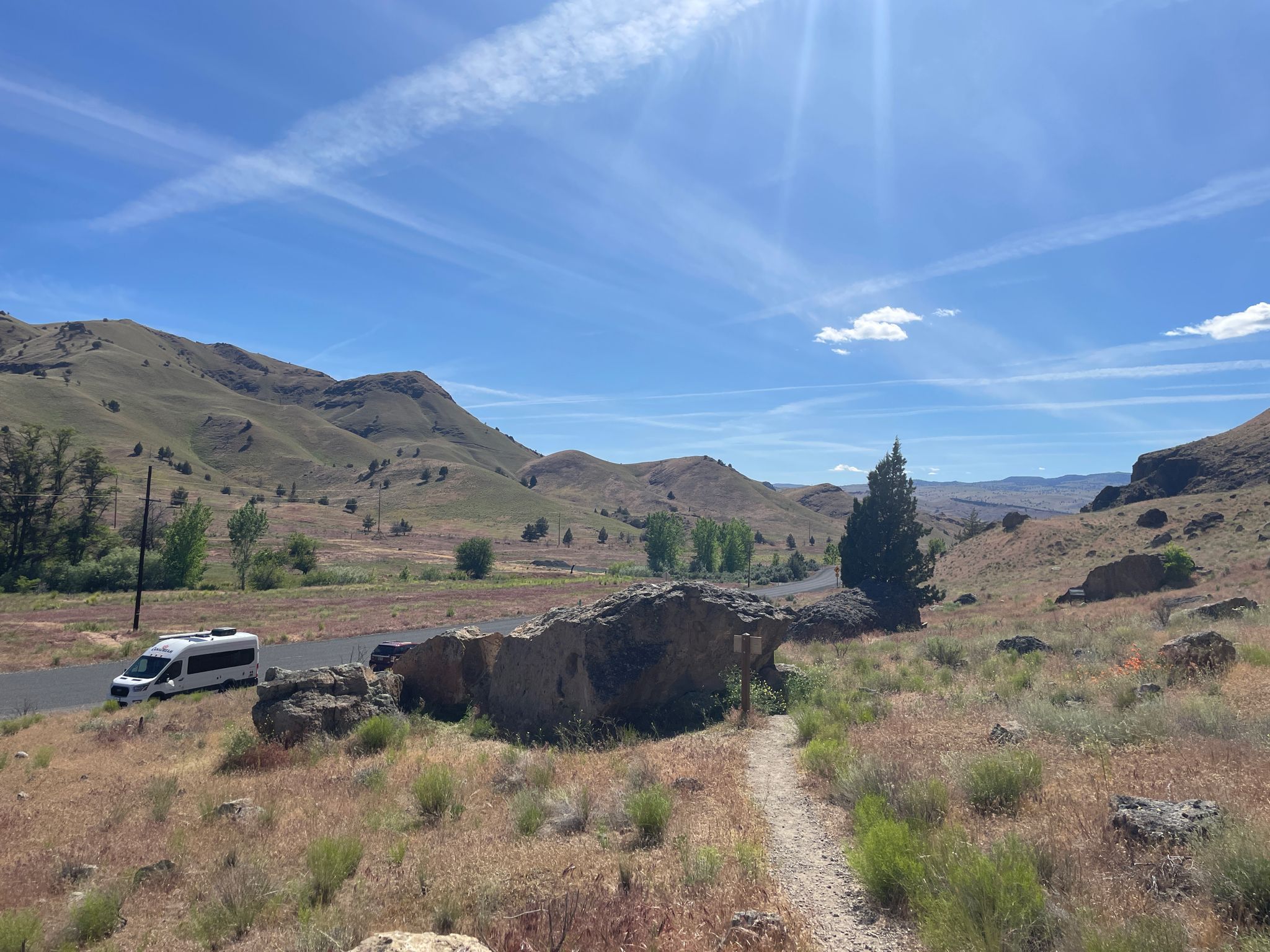 A white van on a road next to dry hills under a bright sky. - Trail of the Fossils – Clarno Arch loop from Fossil