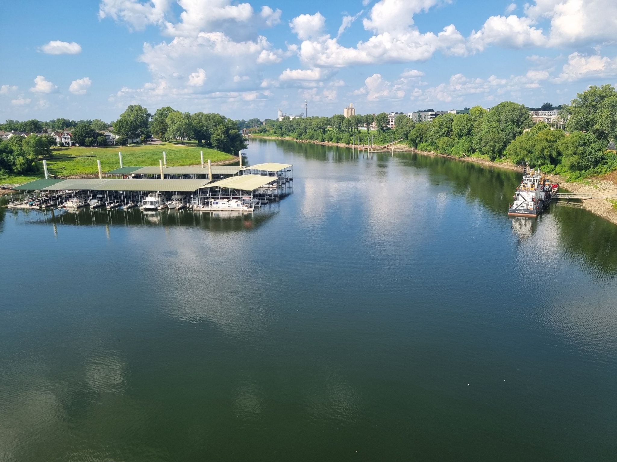 A wide river with boat docks and green trees under a bright blue sky. - View of the Wolf River loop from Memphis