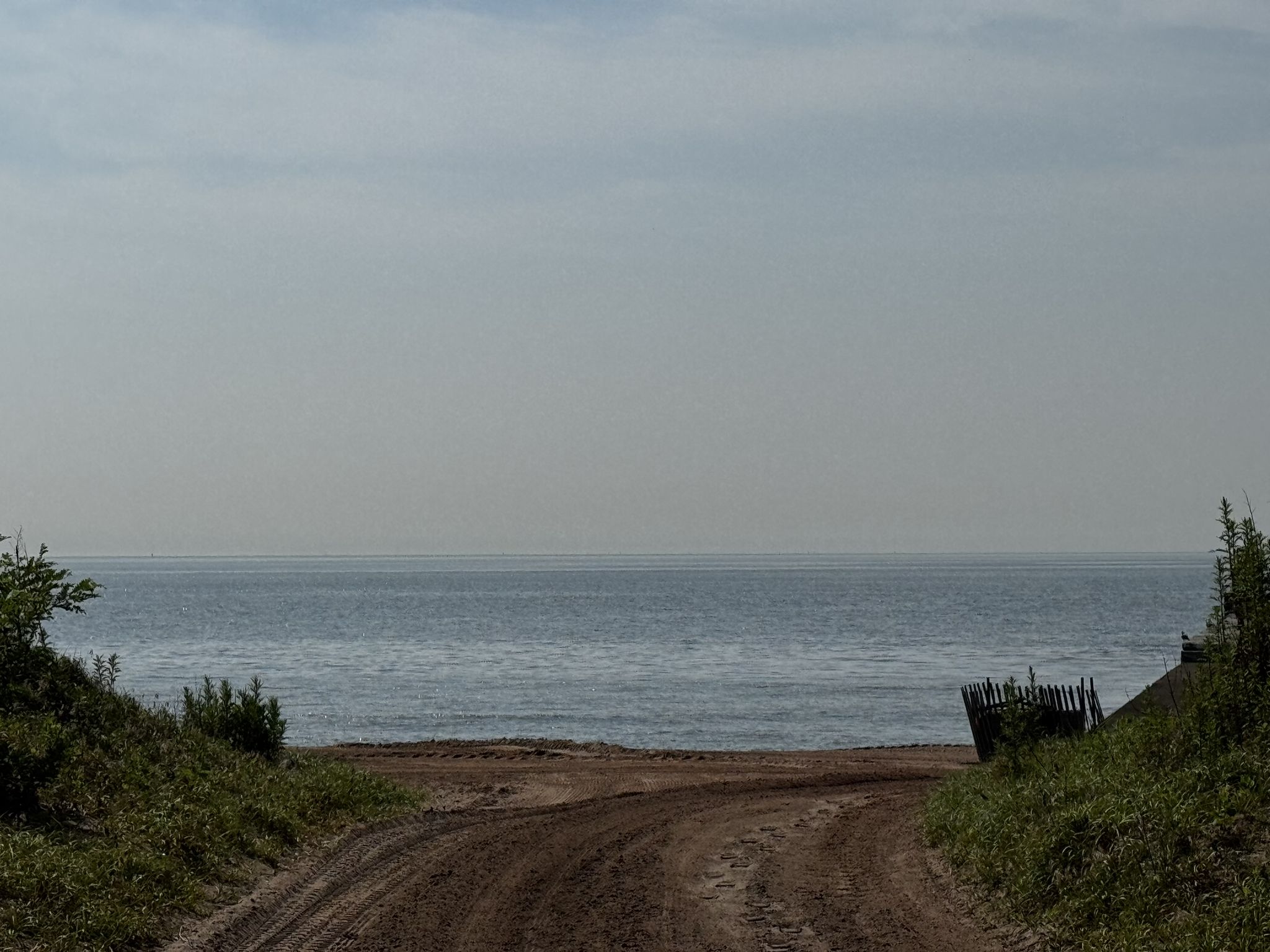 Dirt path leading to a calm ocean under an overcast sky. - Fort Wadsworth — Staten Island – Fort Wadsworth loop from Clifton