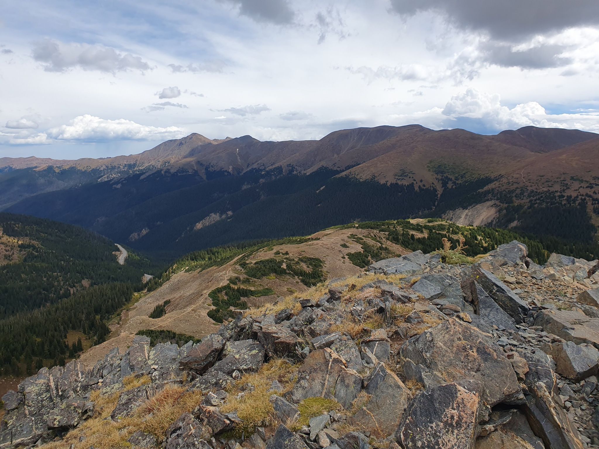 Rocky mountain peak overlooking vast forested valleys under cloudy skies. - Stanley Mountain from Berthoud Pass