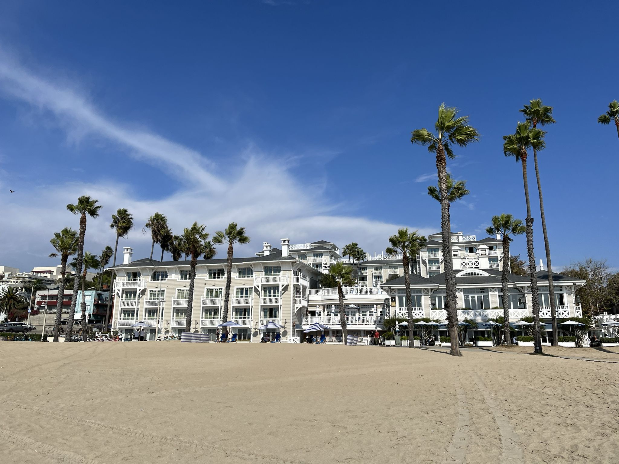 Large white building with palm trees on a sandy beach under a clear blue sky. - Santa Monica State Beach – Santa Monica Pier loop from University of California, Los Angeles