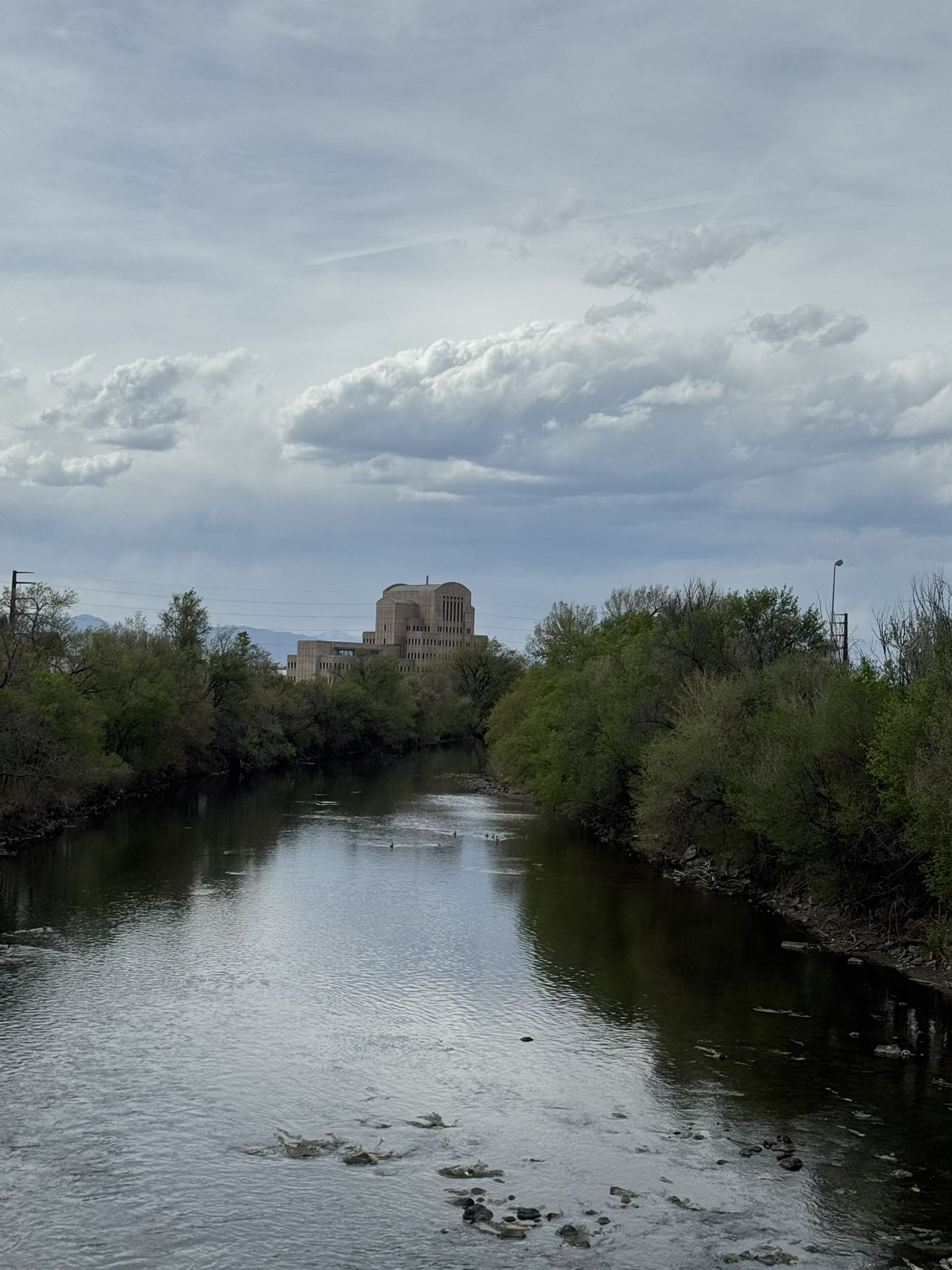 River flowing between lush green trees, with a large building in the distance. - Cherry Creek Trail – Cherry Creek Trail loop from University of Denver
