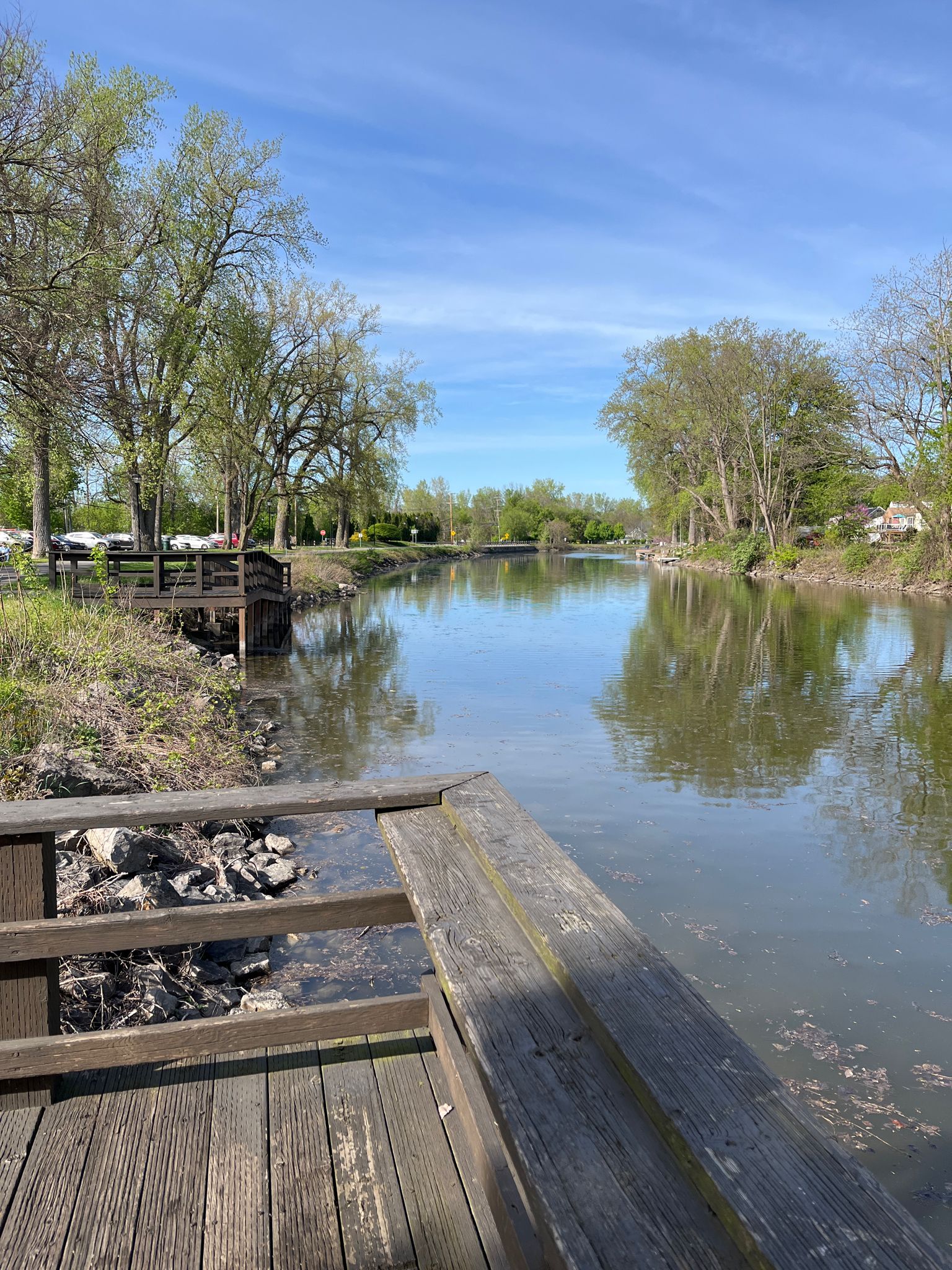A wooden dock overlooks a calm river with trees under a clear blue sky. - Running loop from Fairport