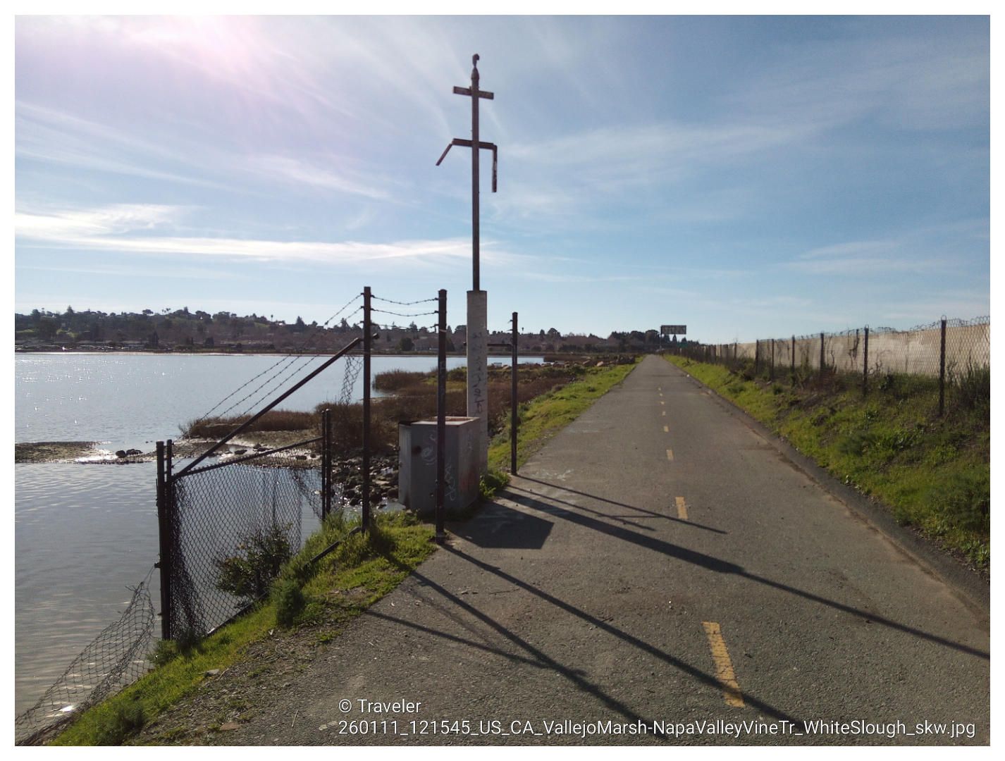 Paved path next to a body of water, with a tall pole and fence. - Vallejo to Sulphur Springs loop via Napa Valley Vine Trail