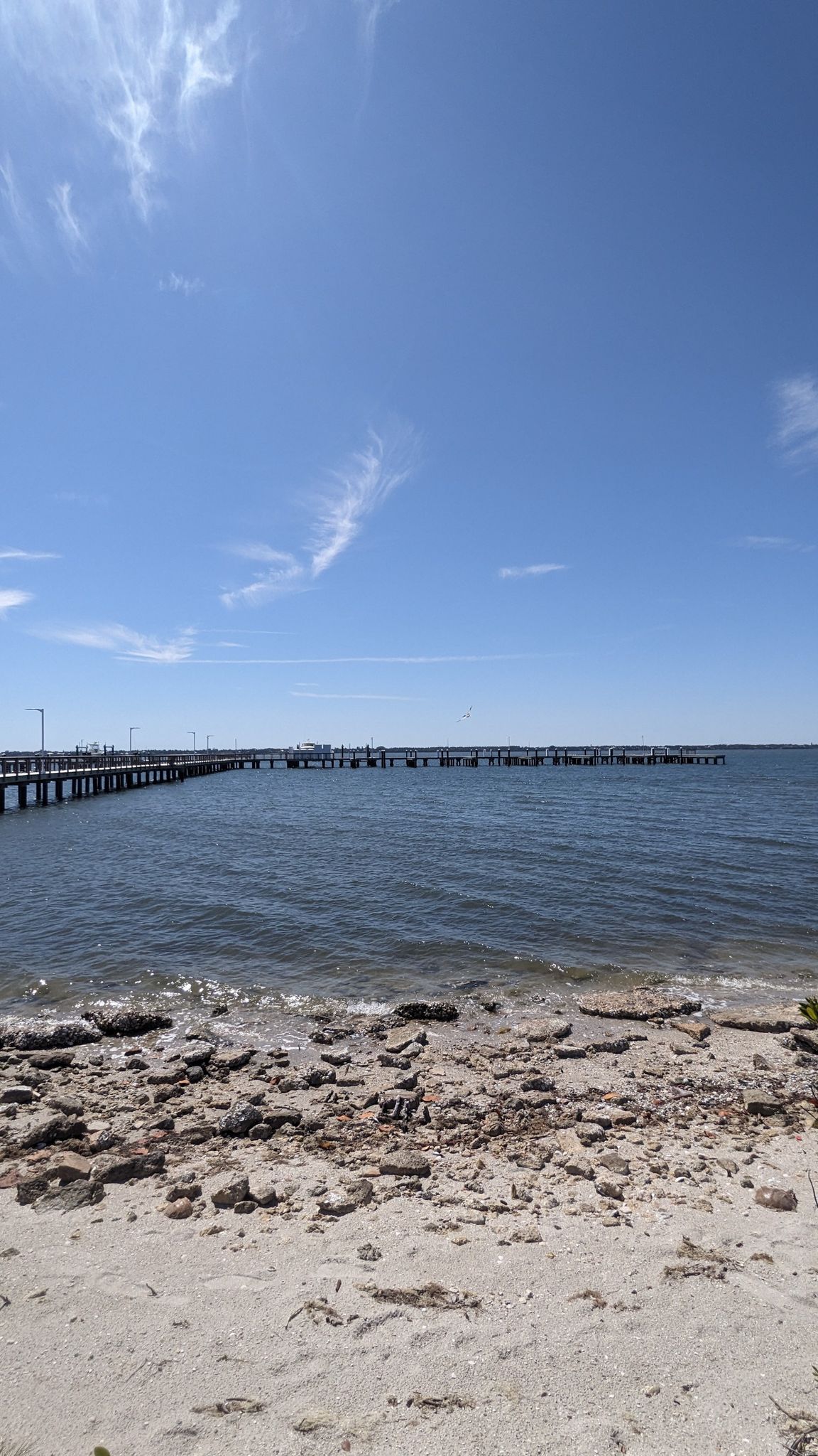 Sandy and rocky beach leading to a long pier over calm water. - Jensen Beach to Fort Pierce loop