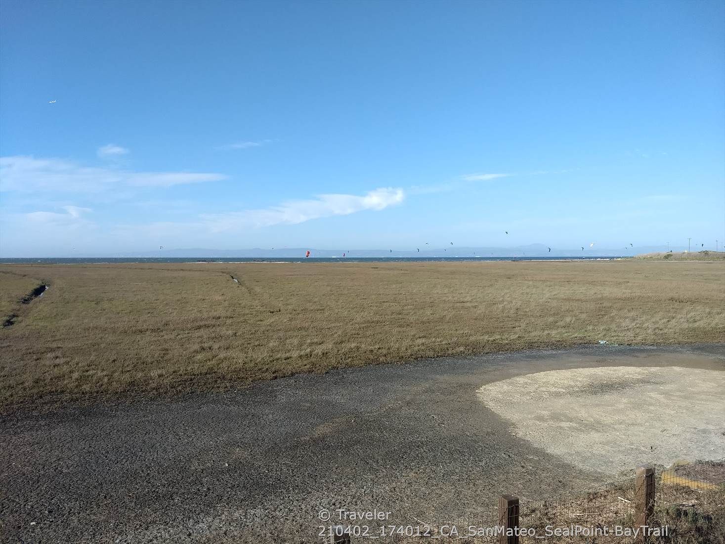 Expansive, dry marshland under a bright blue sky with distant water. - Seal Point Park loop from Foster City