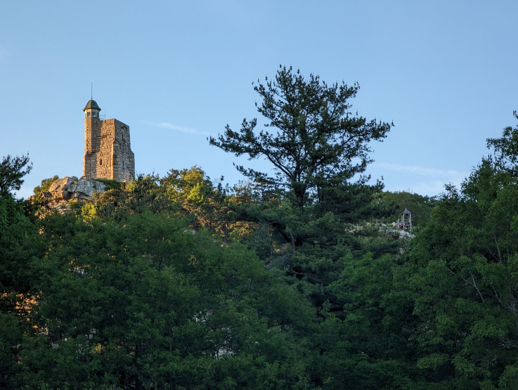An old stone tower stands on a rocky hill above green trees. - Minnewaska State Park Preserve – Overlook loop from Jenny Lane Parking