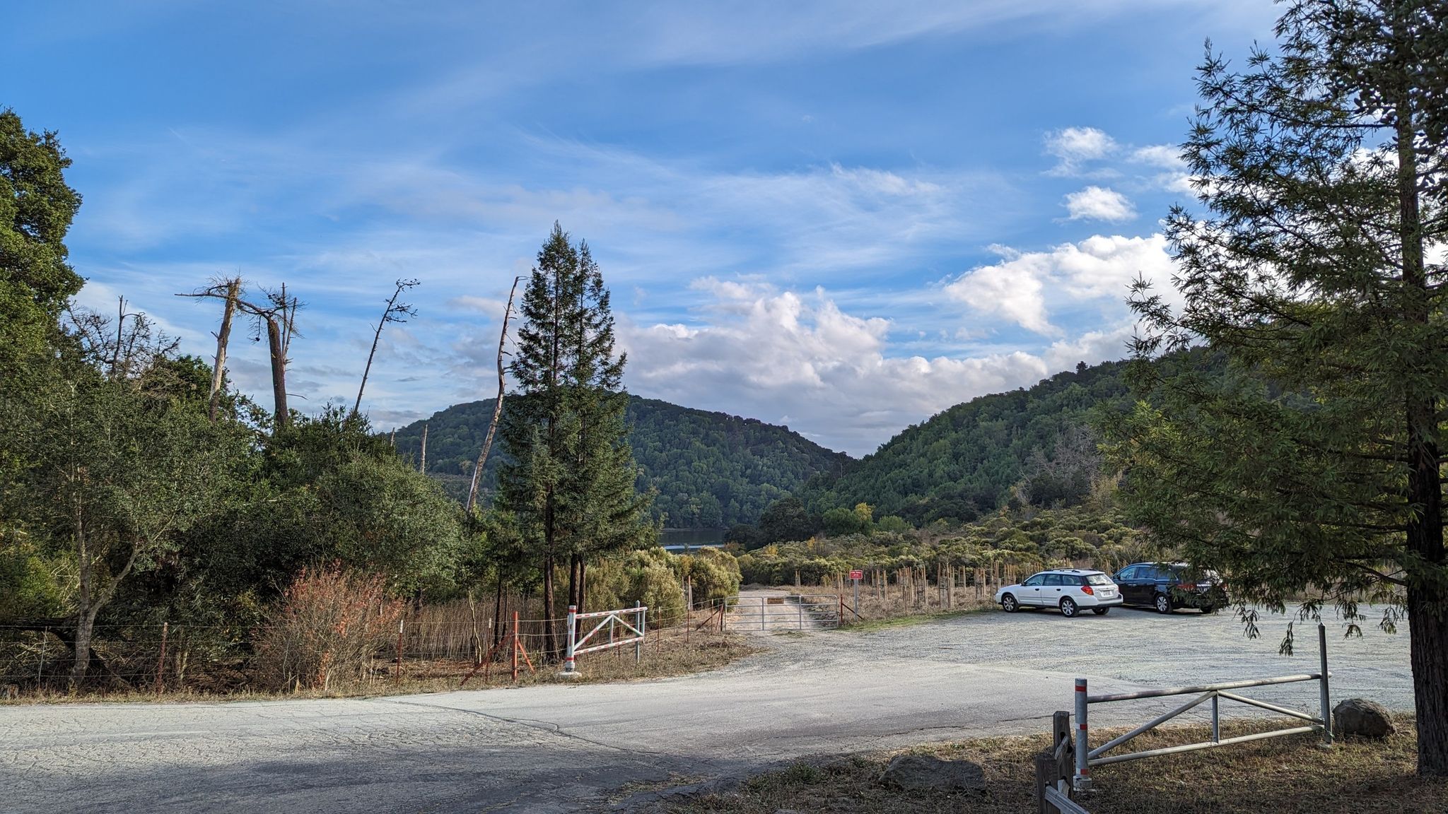 Dirt parking lot with cars, surrounded by trees and hills. - Lamorinda Trail Loop