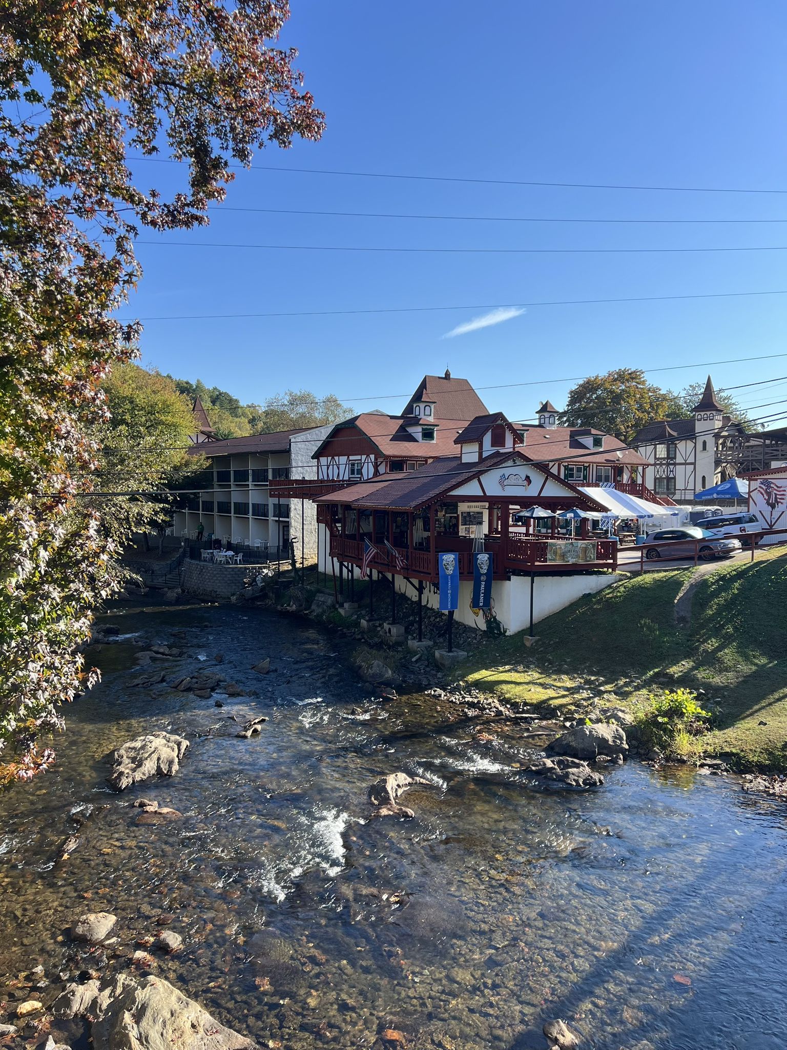 Sunny view of buildings with red roofs beside a rocky river. - Alana Falls – Helen Bavarian Village loop from Helen