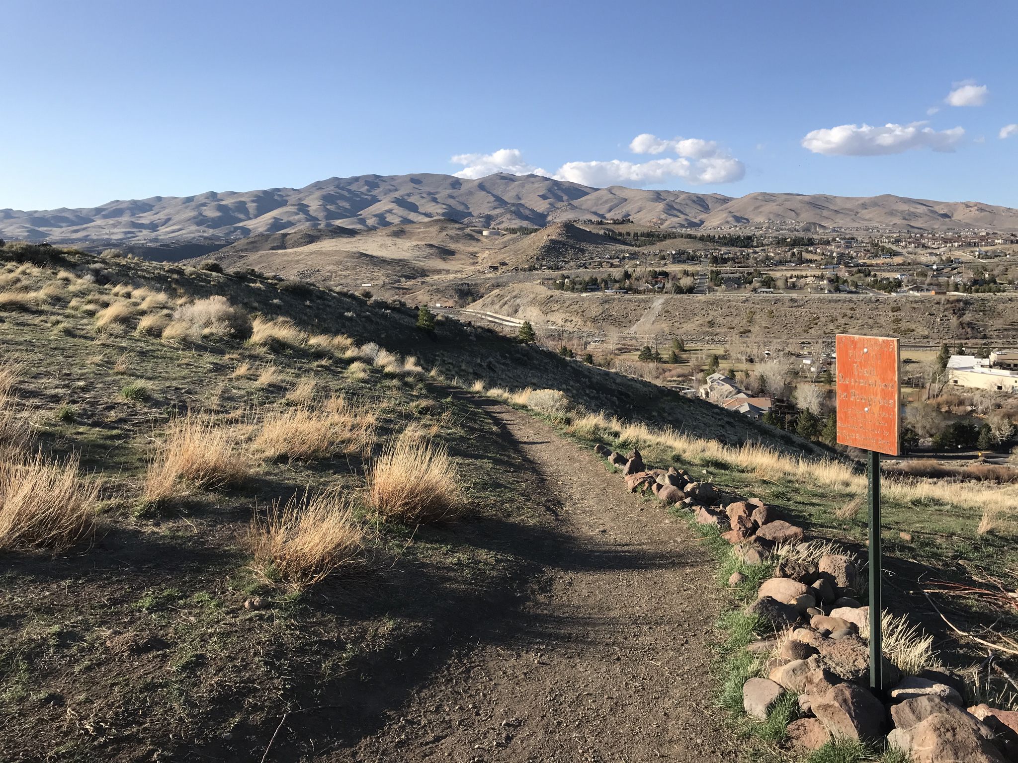 Dirt trail with an orange sign overlooks a valley and distant mountains. - Truckee River – Mayberry Junction loop from Reno
