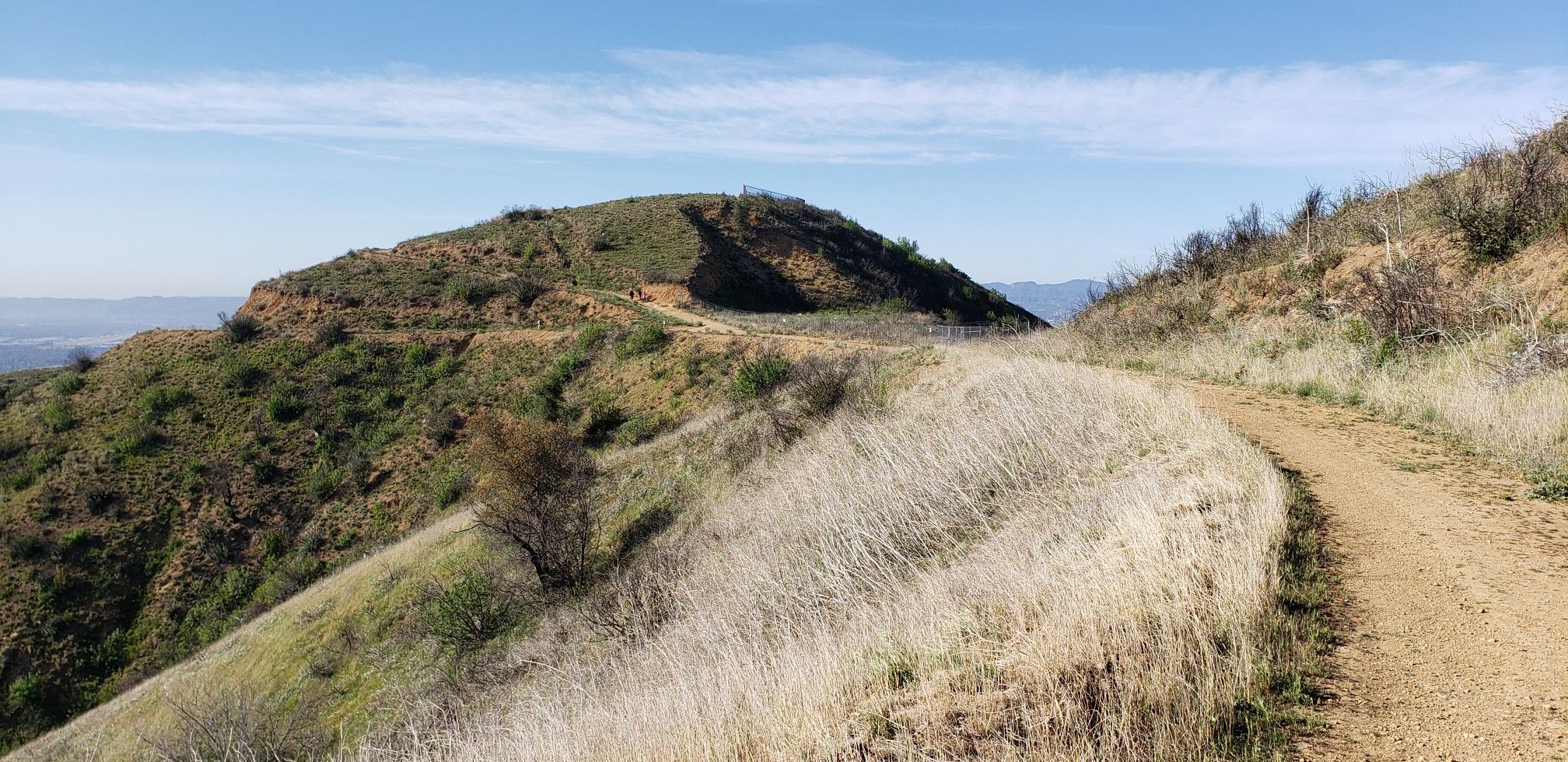 A winding dirt trail on a dry, grassy hillside under a clear sky. - Mission Point and O'Melveny Park Loop