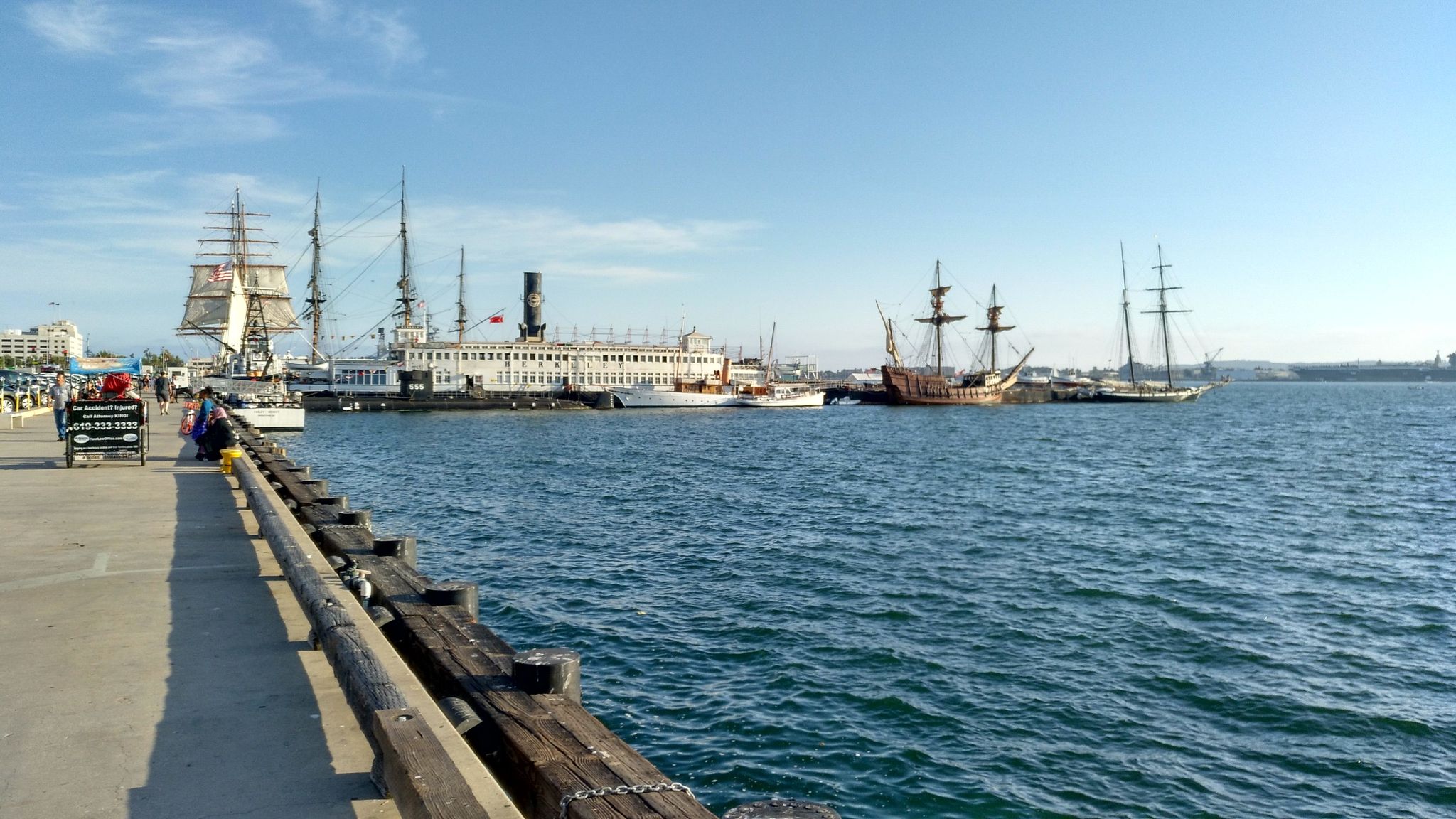 Historic ships docked along a pier next to blue water on a sunny day. - Seaport Village to Point Loma via San Diego Harbor