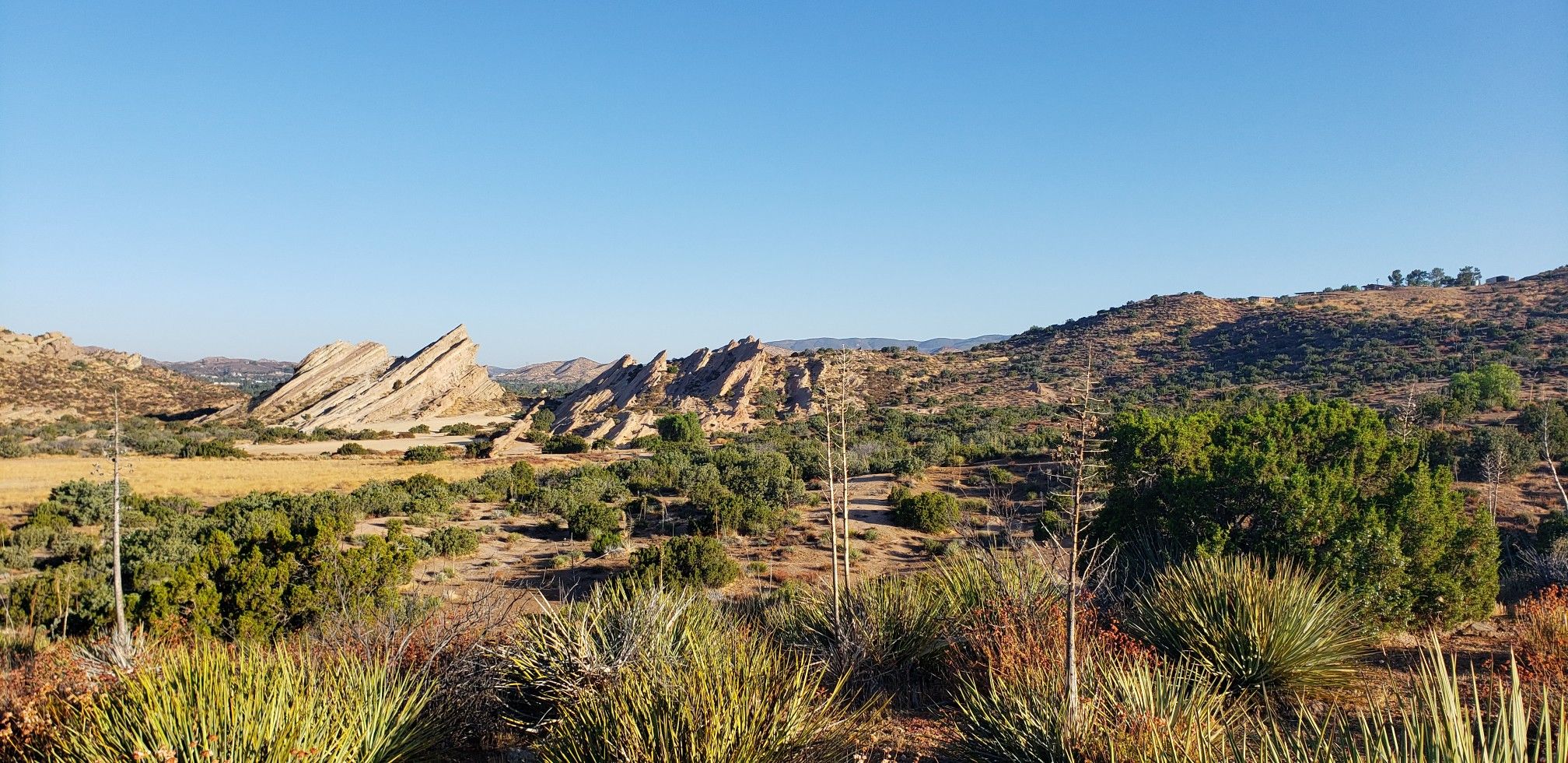 Panoramic view of a rocky desert landscape with distant hills under a clear sky. - Vasquez Rocks area loop from Three Sisters Rock