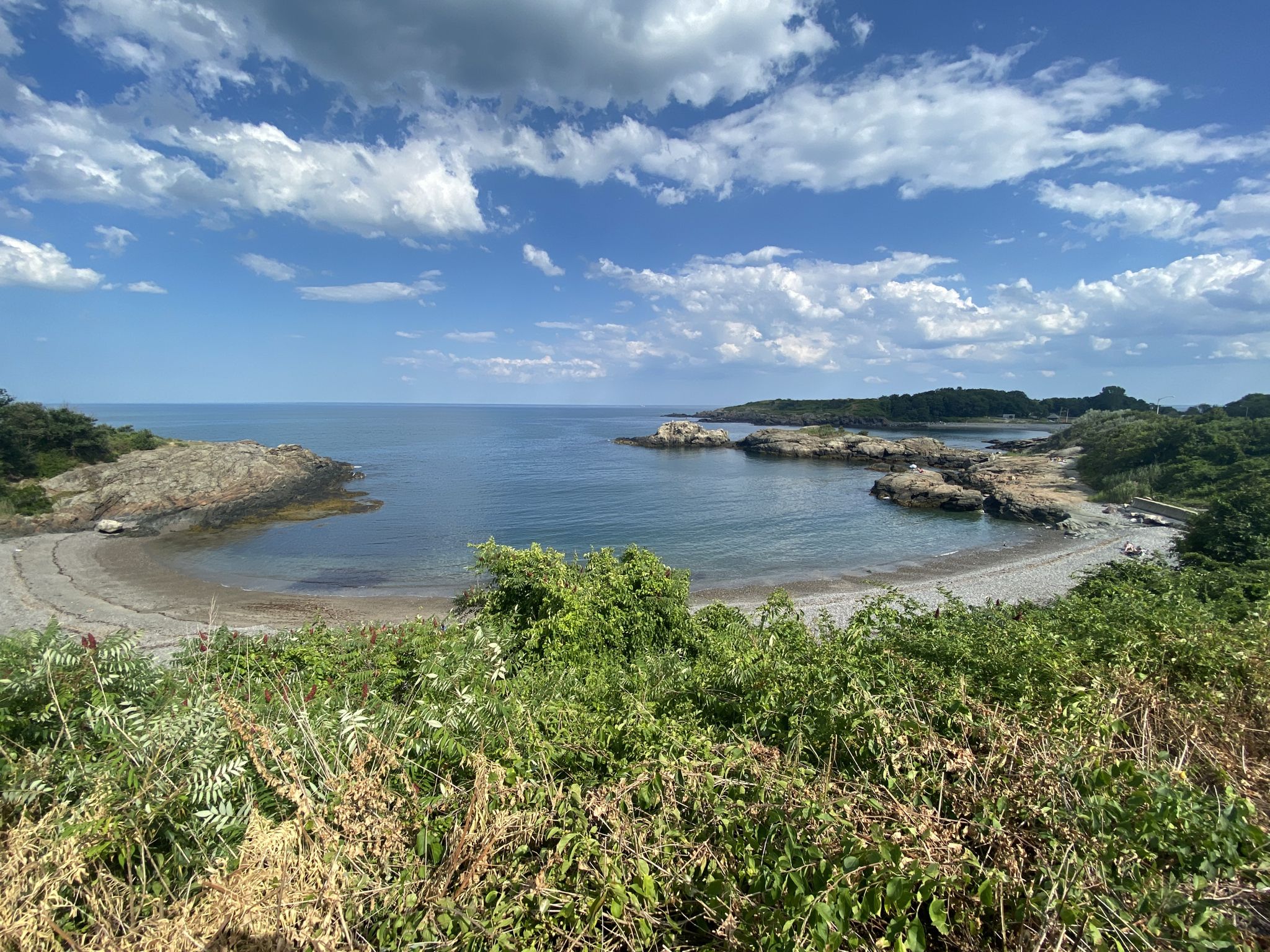 Rocky cove with a small beach, green foliage, and a partly cloudy sky. - Nahant Island & Marblehead loop from Lynn