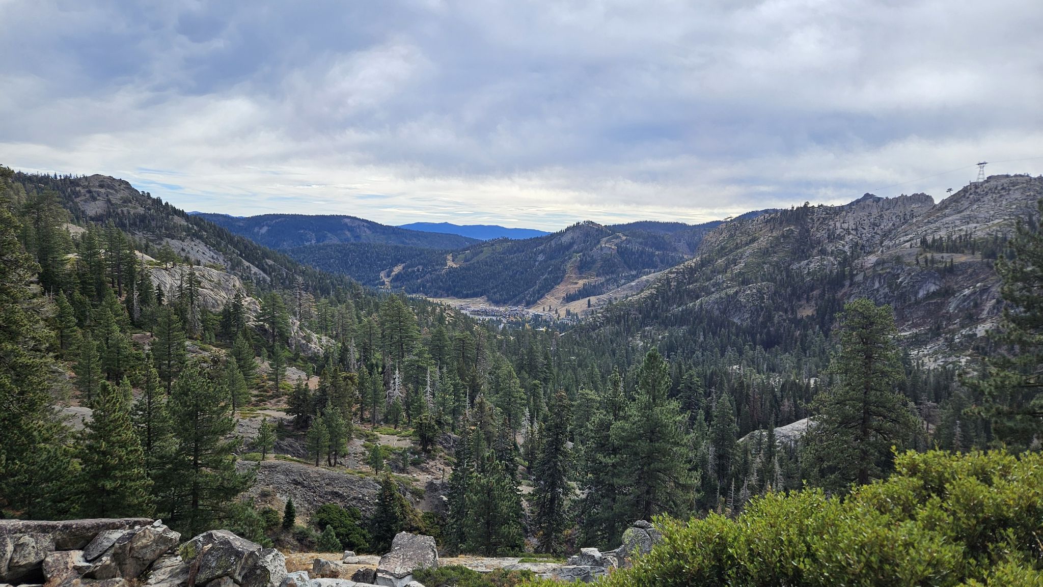 Expansive forested mountain valley with distant hills under a cloudy sky. - Granite Chief Trail and Shirley Canyon Loop