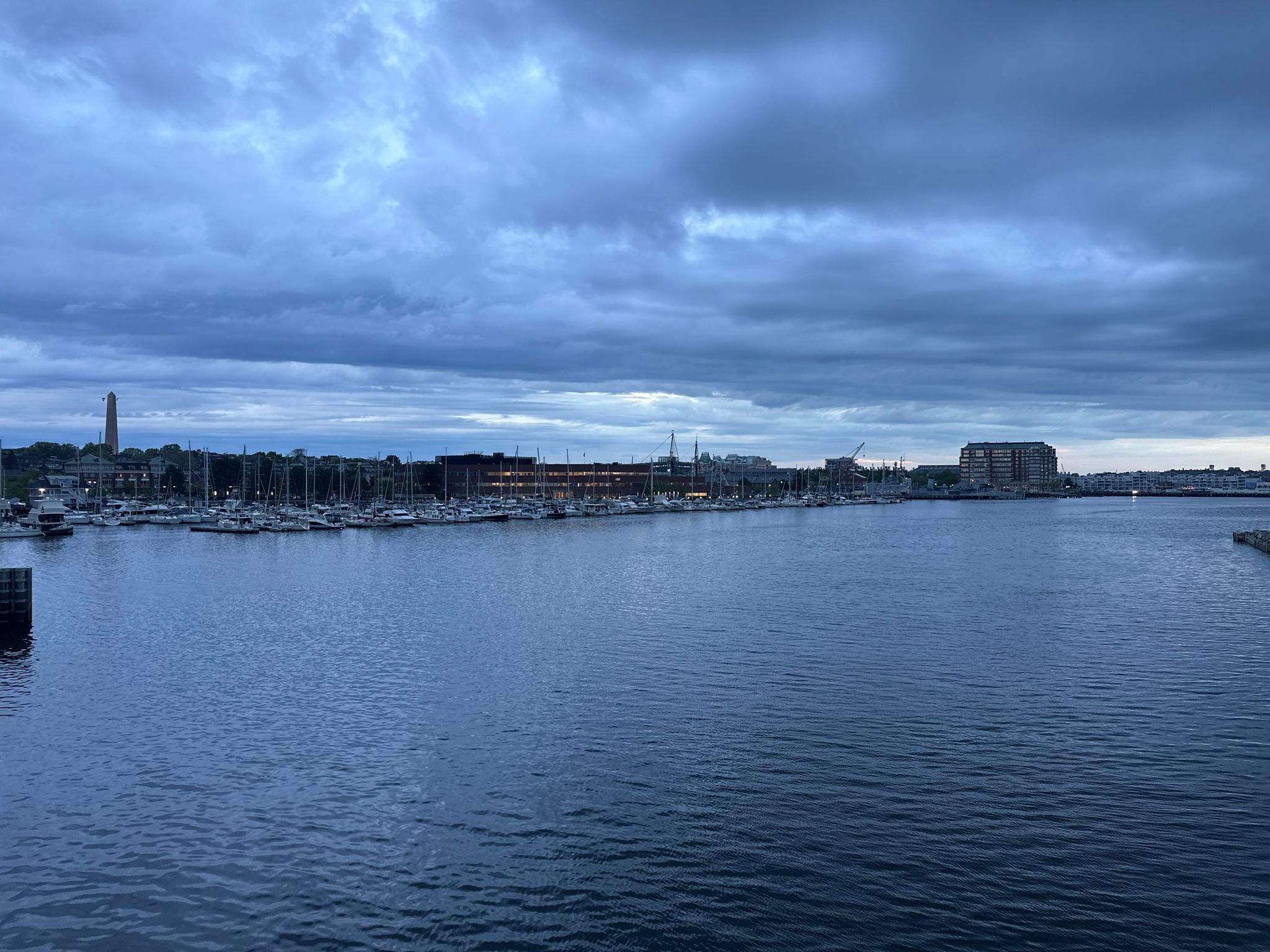 A dark marina with many boats under a heavy, cloudy, twilight sky. - Massachusetts State House – The Boston Public Market loop from Bowdoin