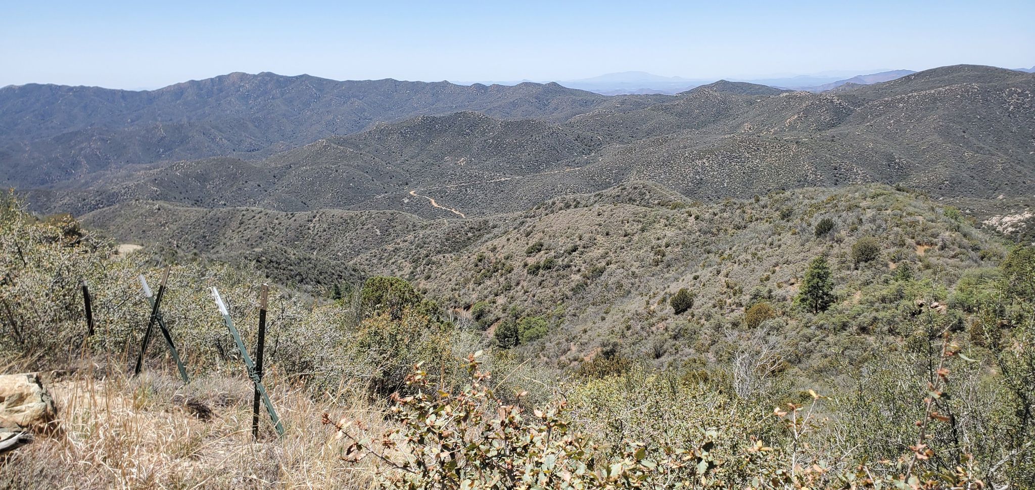 Vast, dry mountainous landscape under clear sky with fence posts in foreground. - Backway to Crown King