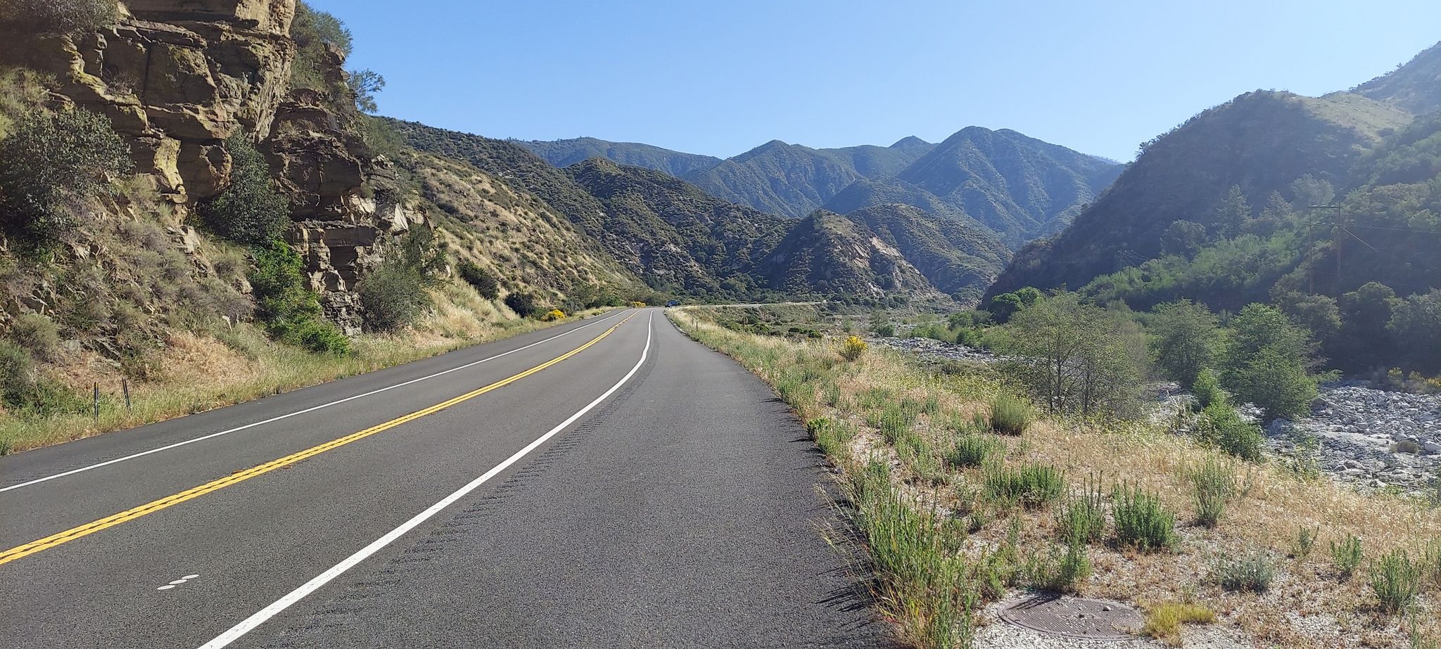 Straight road through a dry riverbed valley with rugged mountains, clear sky. - Santa Ana River Trail and Morton Peak Loop