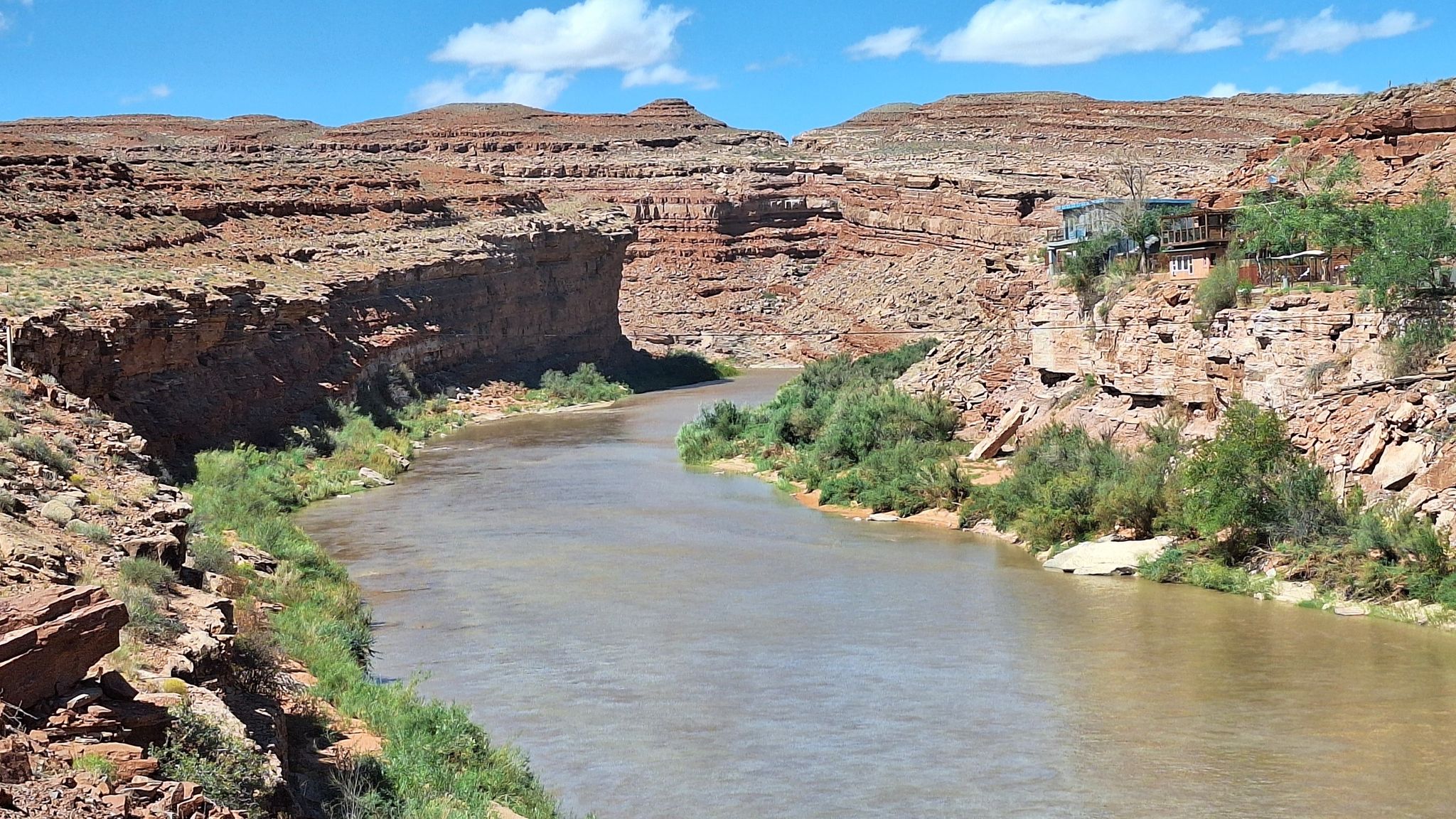 A wide river flows through a red rock canyon under a blue sky. - Bluff Scenic Byway: Bluff to Monument Valley