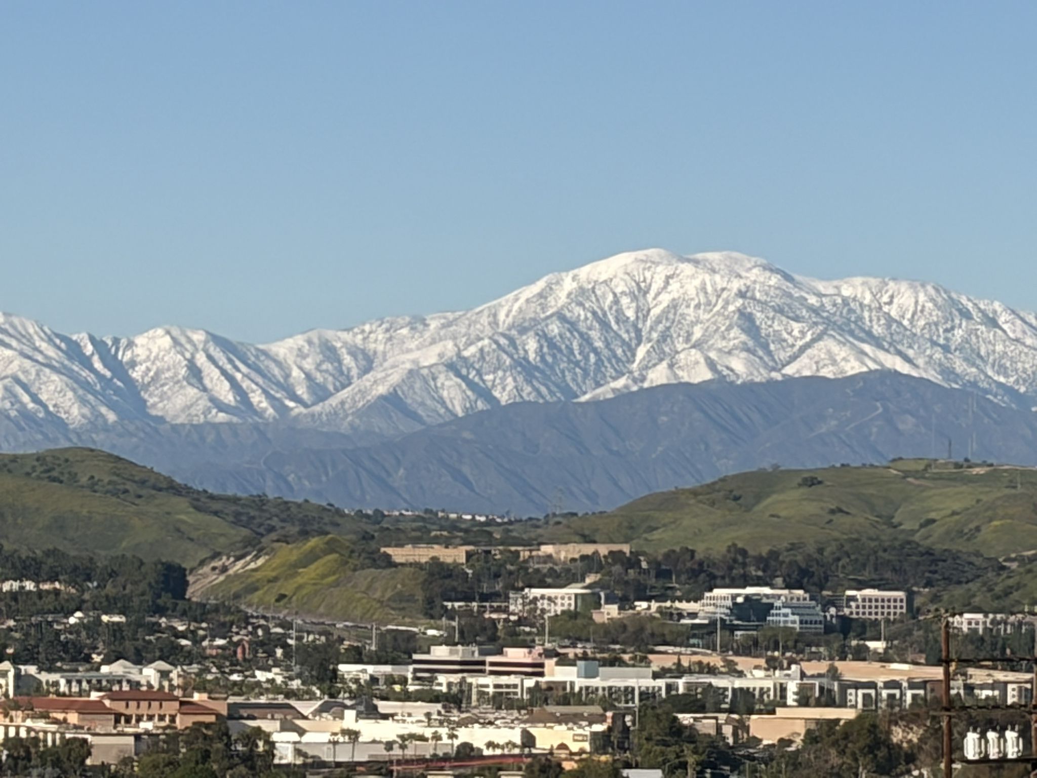 Snow-capped mountains loom over a sprawling city on a clear day. - Laguna Lake – Brea Dam Trail loop from Sunny Hills High School