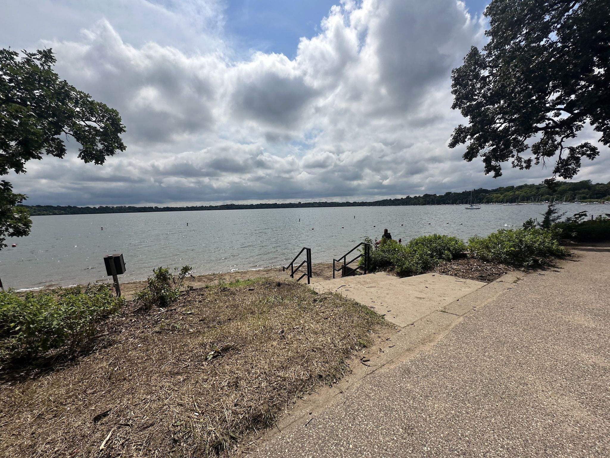 Sandy beach with steps leading to a large lake under a cloudy sky. - Lake Harriet South Beach loop from Southwest