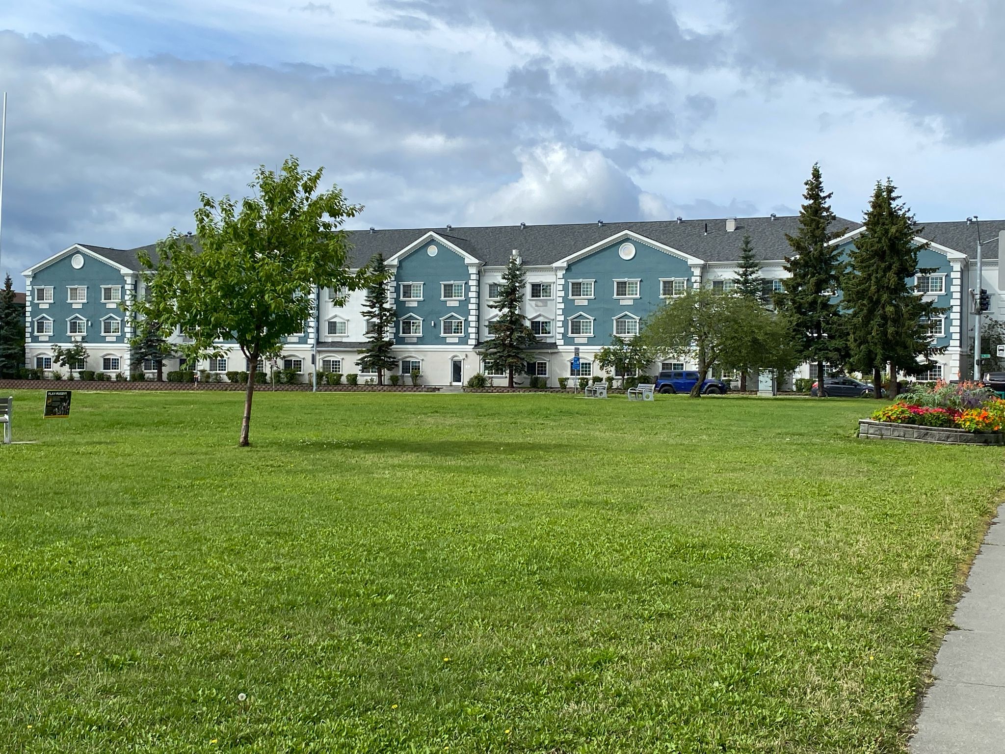 Large blue and white building behind a wide green lawn on an overcast day. - Delaney Park Strip loop