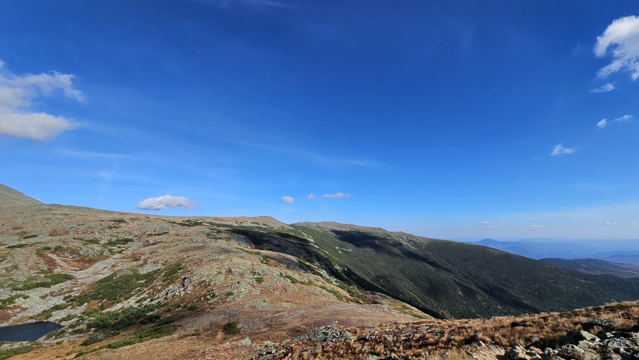 Expansive rocky mountain slopes under a bright blue sky with scattered clouds. - Crawford Path