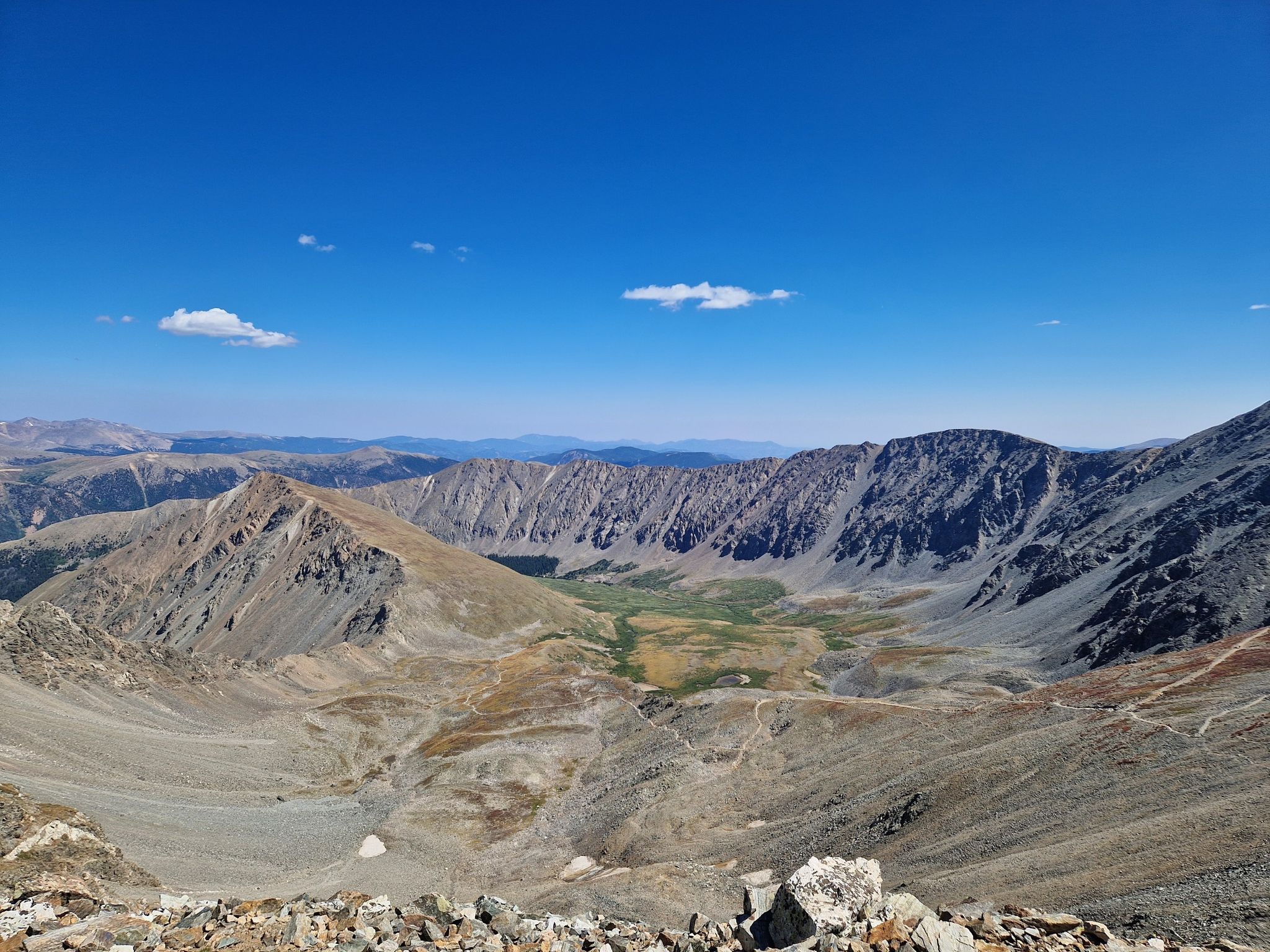 A vast mountain landscape with a green valley under a bright blue sky. - Grays Peak and Torreys Peak Trail