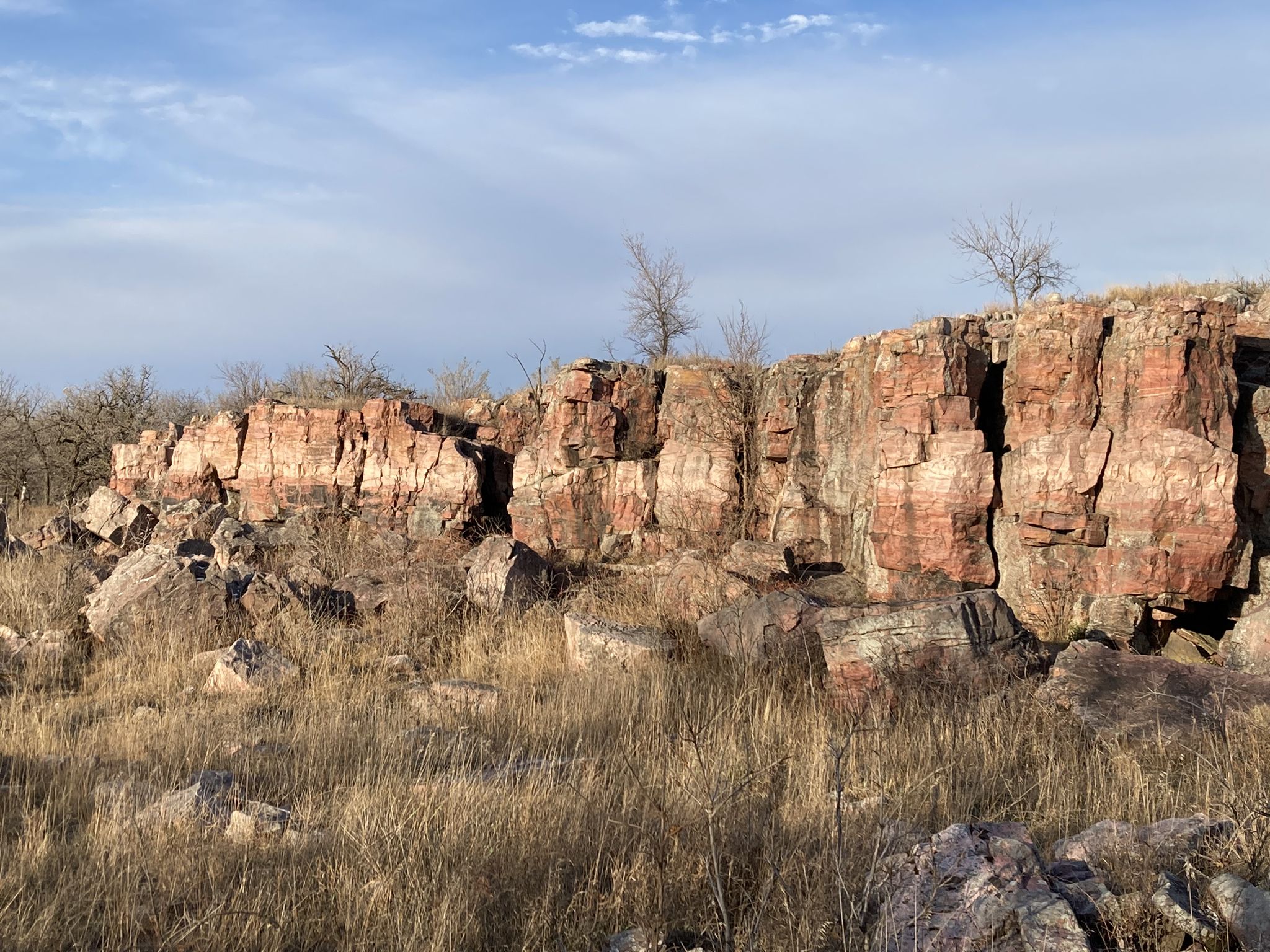 Expansive view of red rock cliffs and boulders amidst dry winter grass. - Circle Trail