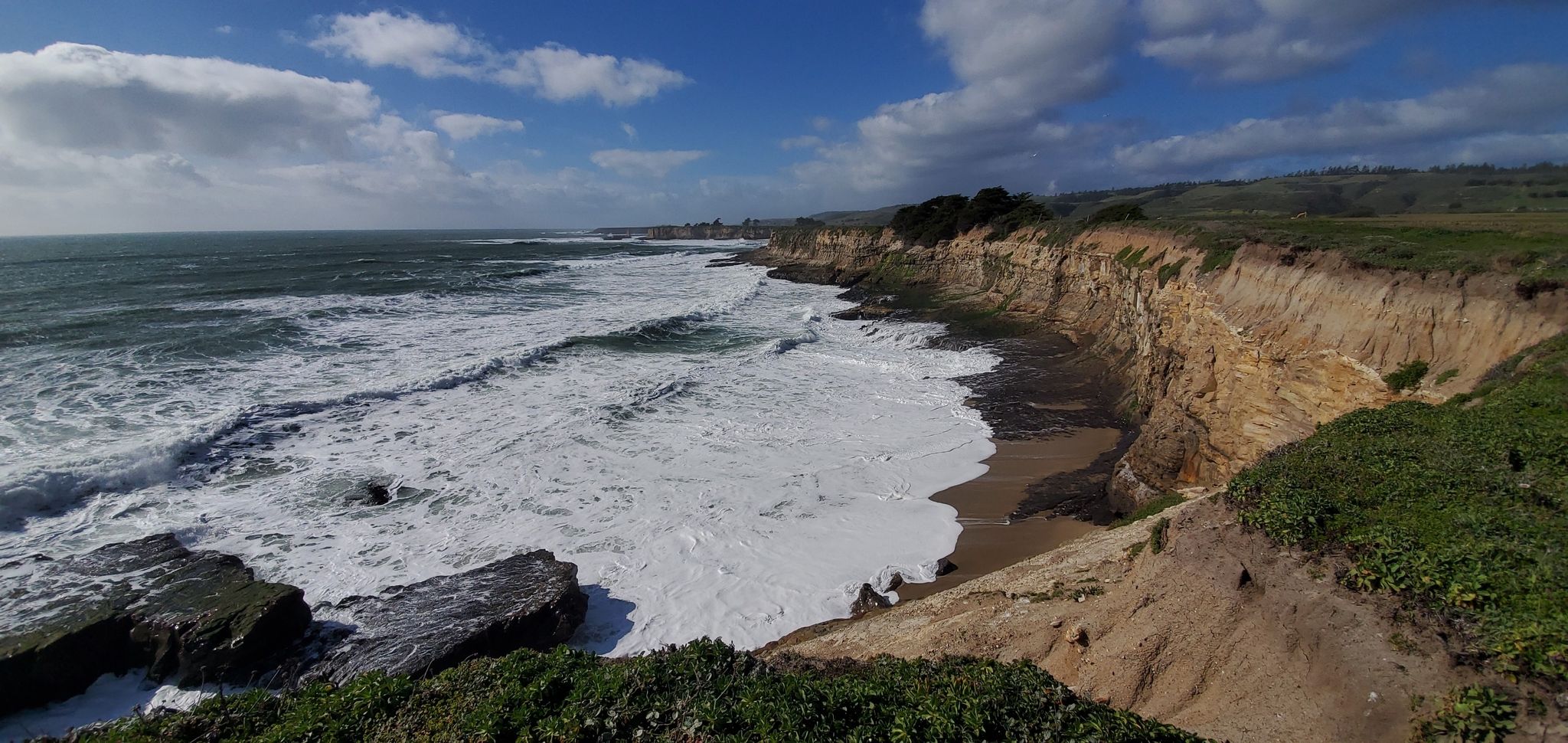 Panoramic view of foamy ocean waves crashing against sandy cliffs under a blue sky. - Wilder Ridge Loop Trail – Wilder Beach Natural Preserve loop from Swift Halt