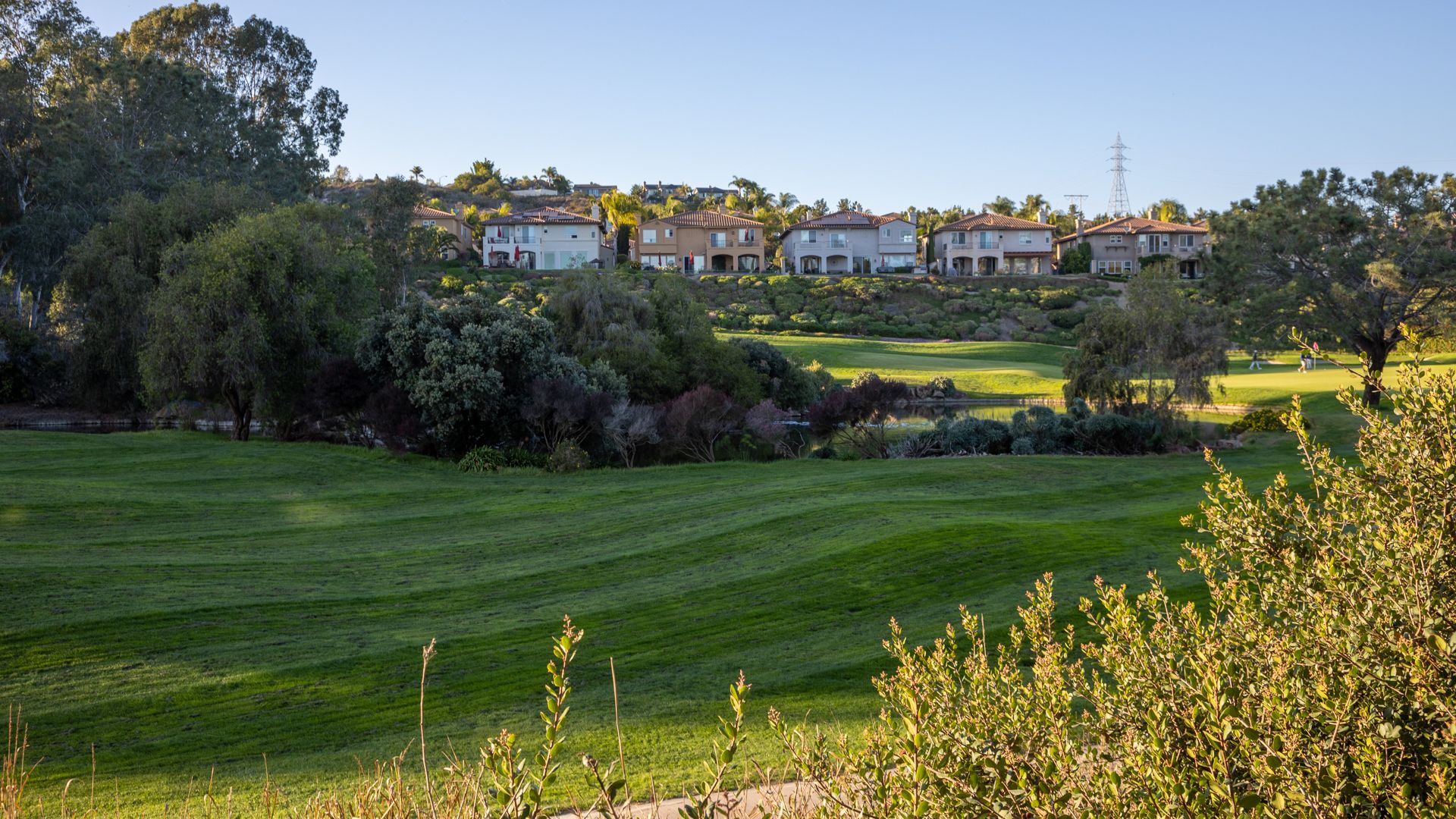 Sunny golf course with green fairways and houses on a distant ridge. - Golf View and Black Sage Trail Loop