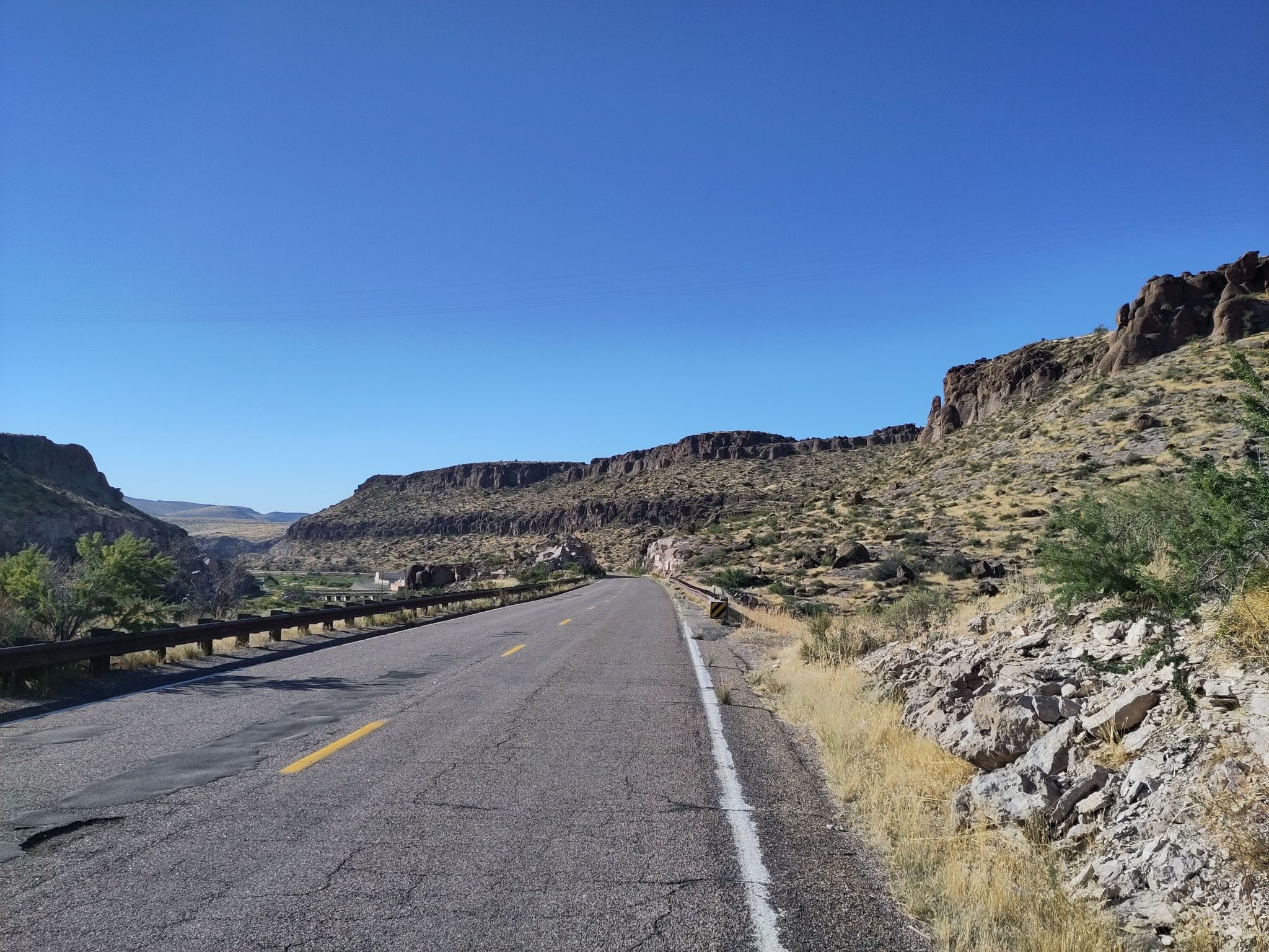 Paved road winding through a desert canyon with rocky hills. - Kingman to Oatman via Route 66