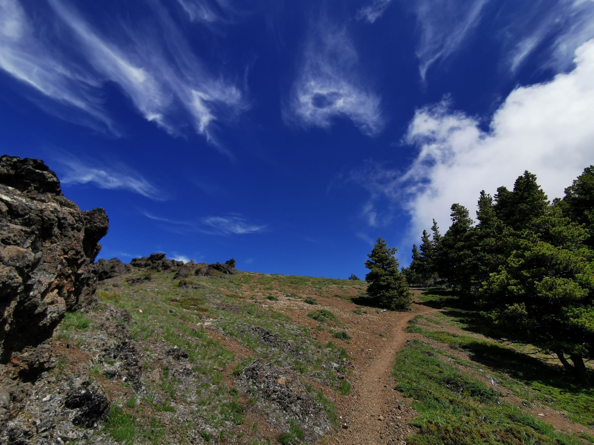 Uphill dirt path through rocky terrain under a bright blue sky. - Mount Townsend via Little Quilcene Trail